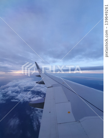 Phone photo of the Earth at twilight, viewed from an airplane. Dramatic aerial scene showing the horizon, fading sunlight, and atmospheric layers from high altitude. Phone photo of the Earth at twilight, viewed from an airplane. Dramatic aerial scene showing the horizon, fading sunlight, and atmospheric layers from high altitude. 139649261