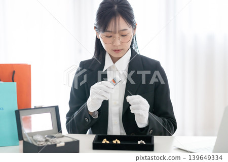 鑑定師正在驗證一隻貴金屬手錶的真偽;他手裡拿著放大鏡;男士手錶;資產價值評估。 鑑定師正在驗證一隻貴金屬手錶的真偽;他手裡拿著放大鏡;男士手錶;資產價值評估。 139649334