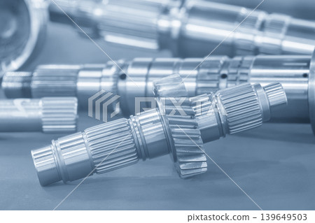 Close-up of a high-precision metal bevel gear on transmission gear parts in a light blue technical scene. Close-up of a high-precision metal bevel gear on transmission gear parts in a light blue technical scene. 139649503