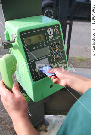 Insert a telephone card into a public telephone. Insert a telephone card into a public telephone. 139649633