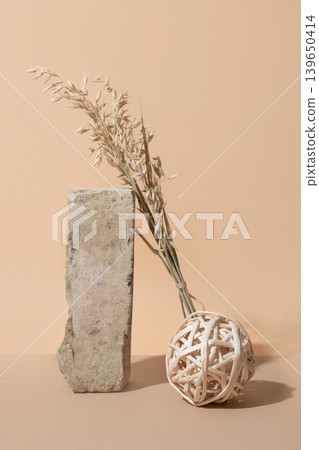 Minimal natural decor with dried oat grass wicker ball and stone block on beige background Minimal natural decor with dried oat grass wicker ball and stone block on beige background 139650414