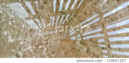 Abstract reflection of a fence in a puddle Abstract reflection of a fence in a puddle 139651167