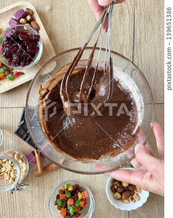 Female hands mixing chocolate dough in a glass bowl. Top view Female hands mixing chocolate dough in a glass bowl. Top view 139651386