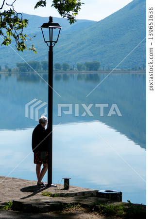 Greece, Kastoria: Woman gazing at Lake Orestiada in Kastoria, Greece Greece, Kastoria: Woman gazing at Lake Orestiada in Kastoria, Greece 139651638