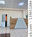 Modern reception area features a wooden front desk, an open door leading to another room, and a potted plant on the counter 139651884