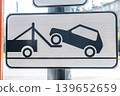 Tow truck sign displays a graphic of a car being lifted onto a flatbed truck, indicating vehicle towing in a public space 139652659