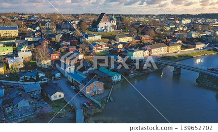 Porvoo, Finland - December 08, 2020: Aerial view showcases a vibrant town along the river, featuring colorful houses, a bridge, and scenic landscapes under a cloudy sky Porvoo, Finland - December 08, 2020: Aerial view showcases a vibrant town along the river, featuring colorful houses, a bridge, and scenic landscapes under a cloudy sky 139652702