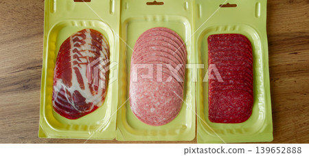 Various types of packaged meats displayed on a wooden surface in a kitchen setting 139652888
