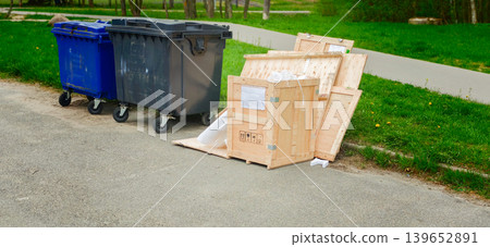 Trash bins and wooden crates left on the ground in a park area during daylight Trash bins and wooden crates left on the ground in a park area during daylight 139652891