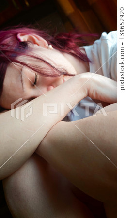 Person resting their head on arms while sitting indoors during daytime 139652920