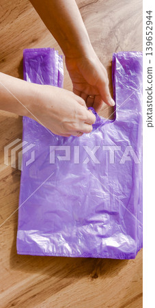 Plastic bags being handled in a room, highlighting pollution issues on Earth 139652944