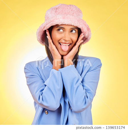 Fashion, tongue and face of Indian woman on yellow background with silly, goofy and playful expression. Emoji, happiness and person in studio with comic pose in trendy accessories, style and hat Fashion, tongue and face of Indian woman on yellow background with silly, goofy and playful expression. Emoji, happiness and person in studio with comic pose in trendy accessories, style and hat 139653174