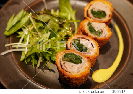特寫鏡頭展示了包裹著京都蔬菜(特別是九條韭菜)的豬排的橫截面。 特寫鏡頭展示了包裹著京都蔬菜(特別是九條韭菜)的豬排的橫截面。 139653261