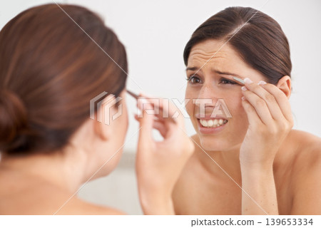 Eyebrow, plucking and woman with pain for beauty, self care and mirror in bathroom. Makeup, routine and girl with hair removal, tools and facial grooming or treatment for skincare and cosmetics Eyebrow, plucking and woman with pain for beauty, self care and mirror in bathroom. Makeup, routine and girl with hair removal, tools and facial grooming or treatment for skincare and cosmetics 139653334