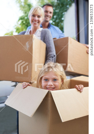 Moving, portrait and girl in box with parent, fun in new home and happy package with mortgage. Mother, father and playful child in cardboard with smile, hiding and property investment for family. Moving, portrait and girl in box with parent, fun in new home and happy package with mortgage. Mother, father and playful child in cardboard with smile, hiding and property investment for family. 139653373