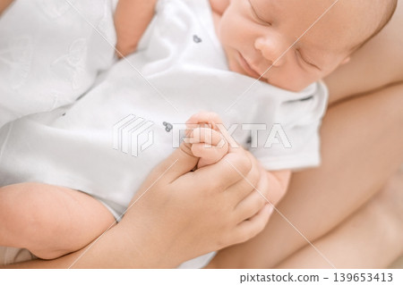 Hands of a newborn baby in close-up, clenched into a fist. A Infant in the arms of his sister 139653413