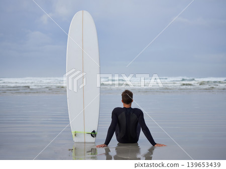 Fitness, beach and man thinking with a surfboard for wellness, sports and training while sitting in nature. Water, exercise and back of male surfer at the ocean with peace, calm and sea hobby in Bali Fitness, beach and man thinking with a surfboard for wellness, sports and training while sitting in nature. Water, exercise and back of male surfer at the ocean with peace, calm and sea hobby in Bali 139653439