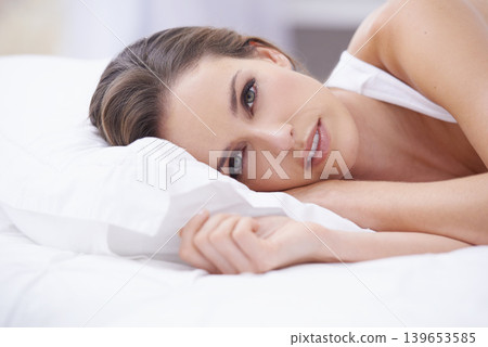 Morning, portrait of woman in bed and relax, wake up and getting ready for a fresh start of new day. Pillow, face and girl in bedroom with rest, wellness and comfort in hotel room, home or apartment. 139653585