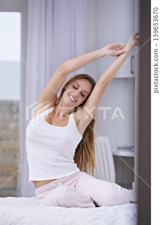 Woman, wake up and stretching in bed on weekend, lazy and comfortable on morning at home. Female person, smile and satisfaction while resting in bedroom, relaxing and good mood on vacation or holiday 139653670