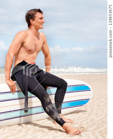 Relax, thinking and shirtless man with surfboard on beach in wetsuit for sports, travel or fitness. Vision, smile and body of young surfer on sand by ocean or sea for exercise, training and workout Relax, thinking and shirtless man with surfboard on beach in wetsuit for sports, travel or fitness. Vision, smile and body of young surfer on sand by ocean or sea for exercise, training and workout 139653675