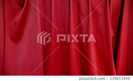 A dramatic drape unfolds against a backdrop of red curtains. A dramatic drape unfolds against a backdrop of red curtains. 139653848