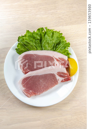 Pork loin steak and lettuce arranged on a white plate. Pork loin steak and lettuce arranged on a white plate. 139653980