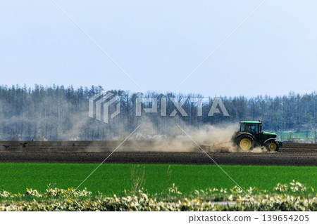A tractor plowing a field in early summer 139654205