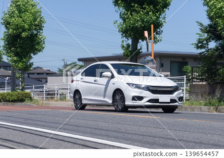 A white hybrid sedan driving on the road A white hybrid sedan driving on the road 139654457