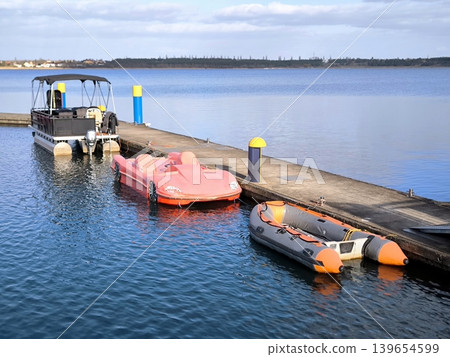 Various types of boats at a concrete pier on the lake. Various types of boats at a concrete pier on the lake. 139654599