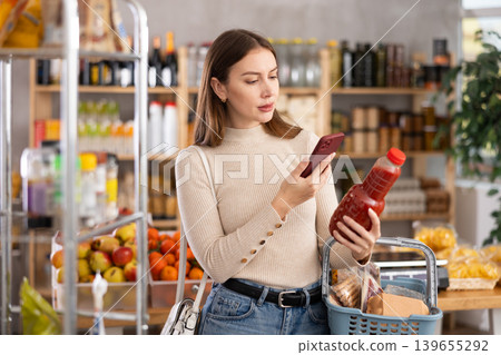 Young woman scanning qr code of tomato juice Young woman scanning qr code of tomato juice 139655292