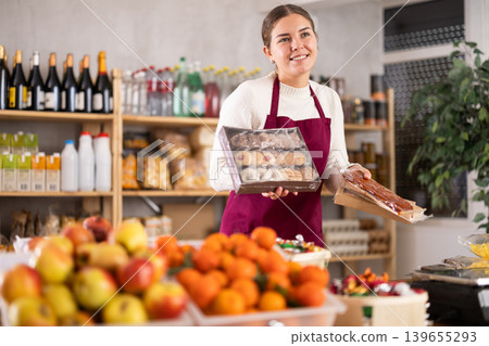 young saleswoman holds cookies and sweets in her hands. young saleswoman holds cookies and sweets in her hands. 139655293