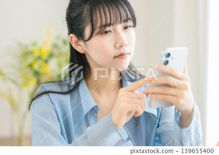 A woman looking at a smartphone thinking A woman looking at a smartphone thinking 139655400