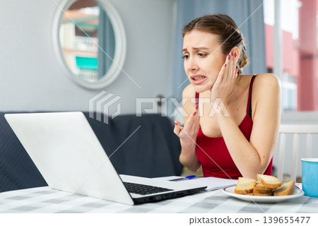Woman with toothache having online consultation at home Woman with toothache having online consultation at home 139655477
