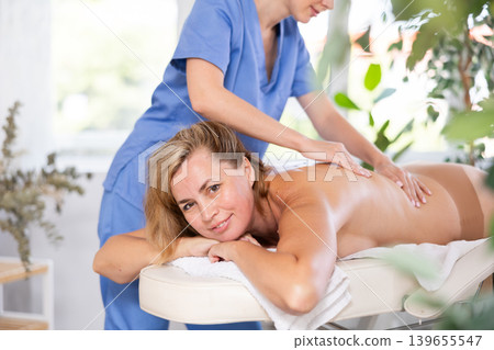 Portrait of young female which is lying on massage table in spa salon Portrait of young female which is lying on massage table in spa salon 139655547