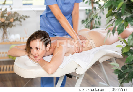 Relaxation. Masseur doing massage on woman body in spa salon. Beauty treatment concept Relaxation. Masseur doing massage on woman body in spa salon. Beauty treatment concept 139655551