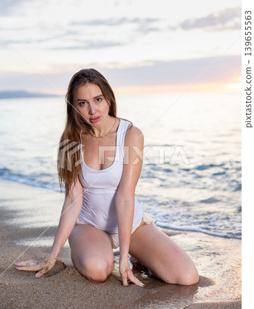 Attractive woman posing on sandy sea beach at sunset background 139655563