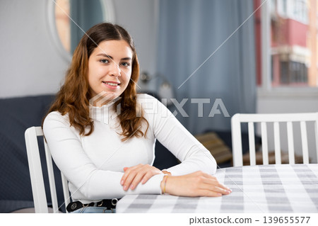 Portrait of young woman sitting at table at home Portrait of young woman sitting at table at home 139655577