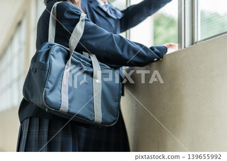 Junior high school girls in uniforms talking in the school corridor 139655992