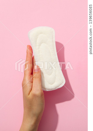 A person holds a sanitary pad against a simple pink background A person holds a sanitary pad against a simple pink background 139656085