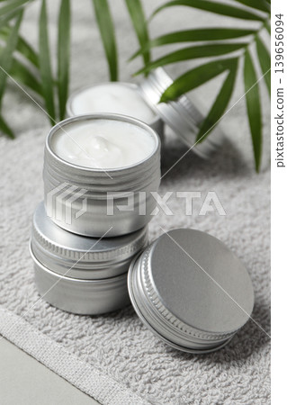 Stacked silver containers hold white cream beside green leaves Stacked silver containers hold white cream beside green leaves 139656094