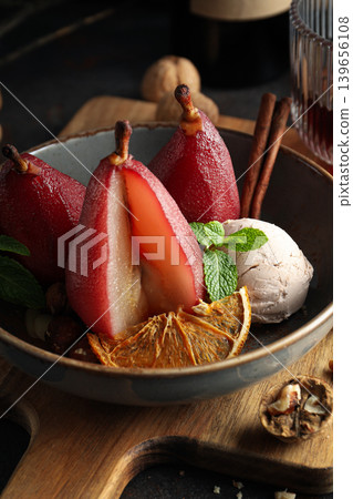Red pears sit in a bowl with ice cream and spices 139656108
