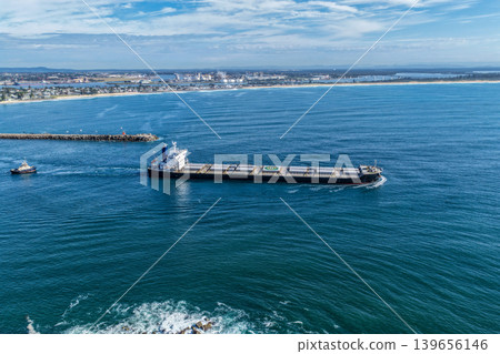 Aerial drone view of a large cargo ship departing Newcastle Harbour in New South Wales, Australia. 139656146