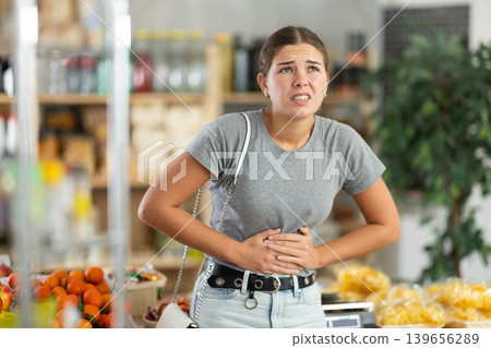 Young woman with stomach pain in grocery store 139656289
