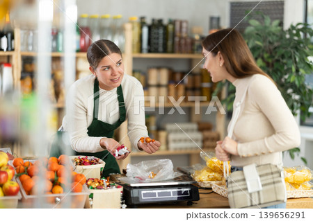 Female vendor weighs candies on scales and sells candies to customer Female vendor weighs candies on scales and sells candies to customer 139656291
