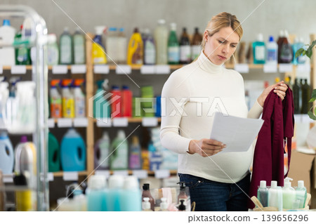 Distressed pregnant store worker reading termination papers Distressed pregnant store worker reading termination papers 139656296