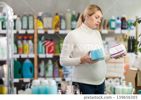 Young pregnant woman choosing feminine pads in personal care store 139656305