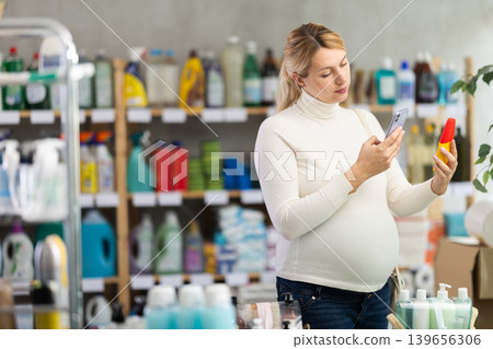 Pregnant shopper scanning barcode on sun lotion with phone 139656306