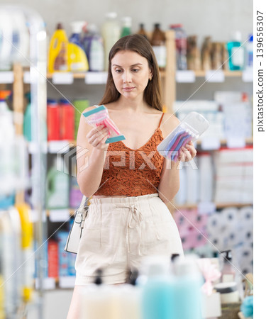 Young woman in summer clothes choosing razor in retail store Young woman in summer clothes choosing razor in retail store 139656307