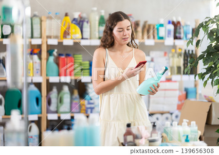Young woman scanning bottle of glass cleaner in store Young woman scanning bottle of glass cleaner in store 139656308