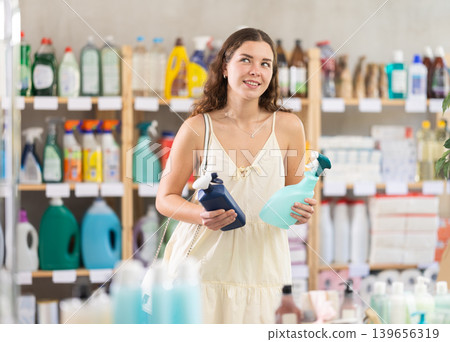 Young woman choosing cleaning spray in household store Young woman choosing cleaning spray in household store 139656319